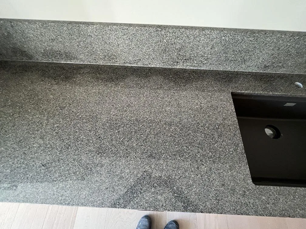 Bänkskiva i polerad Bohus Grå granit med svart underlimmad diskho och uppvikt stänkskydd i Stockholm.