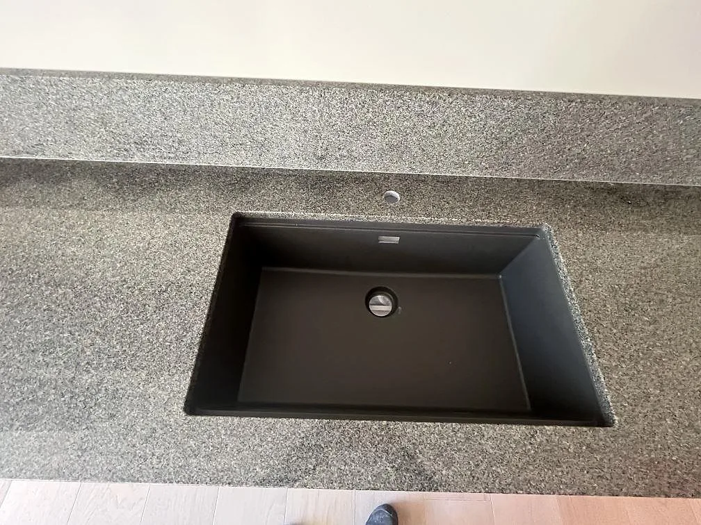 Underlimmad svart diskho i polerad Bohus Grå granit med stänkskydd bakom i Stockholm.