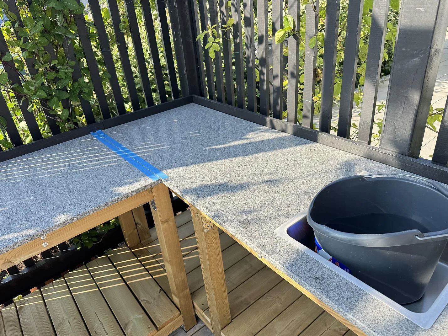 Hörnvy över matt Bohus Grå granit i utekök i Torslanda, med tejpad skarv och urtag i den installerade bänkskivan.
