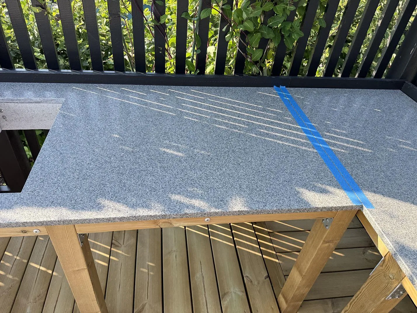 Detalj av matt Bohus Grå granit i Torslanda med tejpad skarv, synlig kant och kornig grå yta på uteköksbänken.