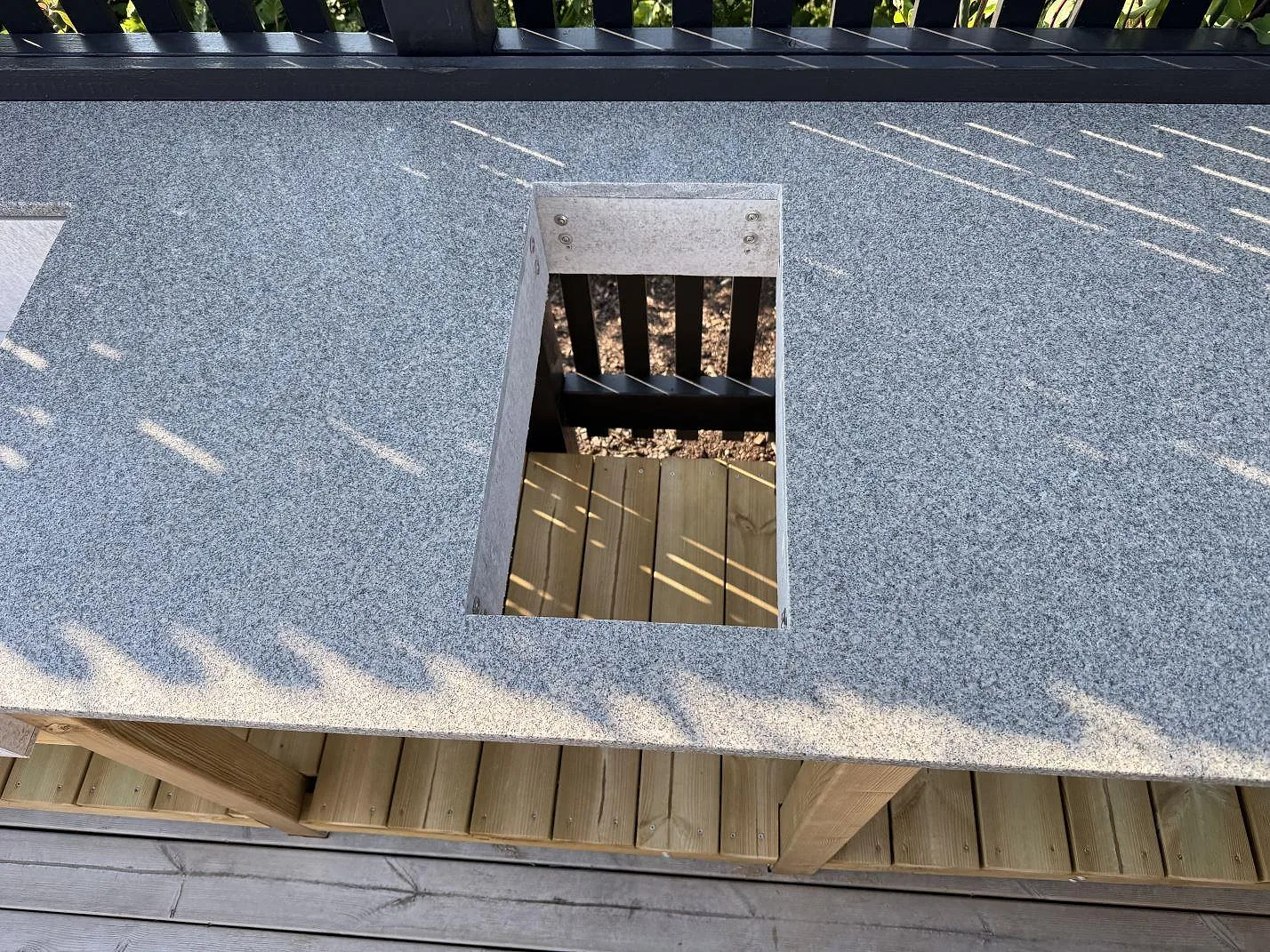 Urtag i matt Bohus Grå granit på uteköksbänk i Torslanda, med tydlig stenkant och trätrall under.