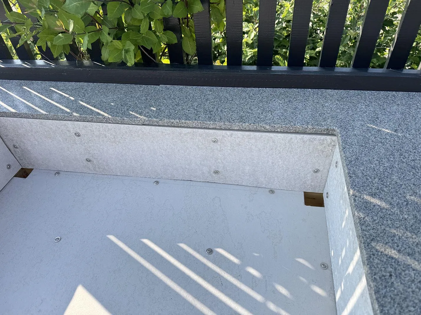 Detalj av öppet underrede under matt Bohus Grå granit i Torslanda, där stenkanten möter den rektangulära modulen.