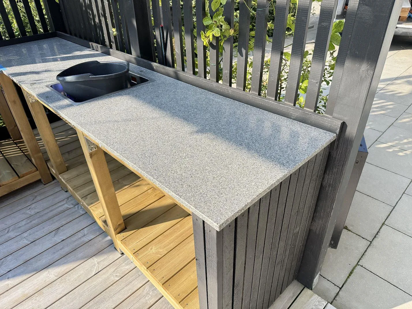Matt Bohus Grå granit som uteköksbänk på trästomme vid altanräcke i Torslanda, med rektangulärt urtag och lång arbetsyta.