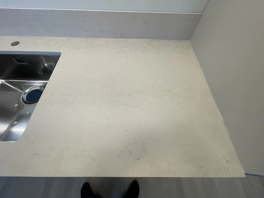 Detalj av polerad Bohus Grå granit vid diskhohörnet, med ljus kornbild och stänkkant i Upplands Väsby.
