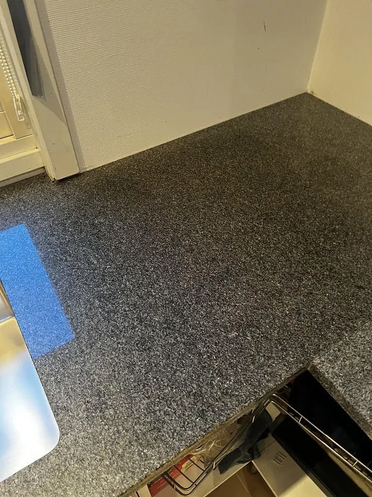 Köksbänkskiva i Bohus Grå granit, polerad, monterad runt ett hörn vid öppna skåp i Växjö.