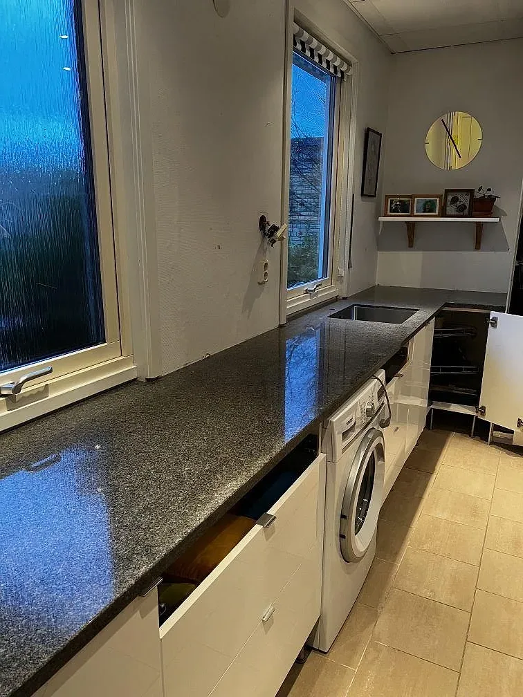 L-formad köksbänkskiva i polerad Bohus Grå granit med rostfri diskho i ett kök under montering i Växjö.