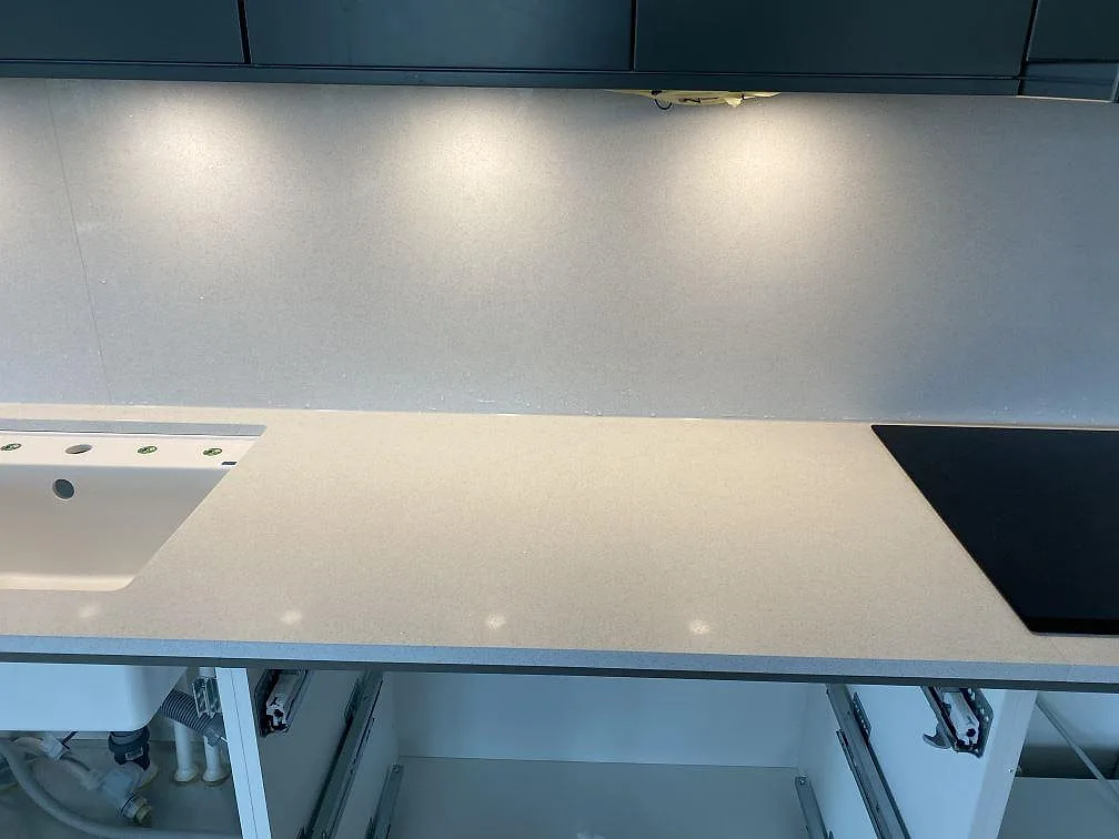 Vit Brilliant White köksbänkskiva ovanifrån med underlimmad diskho och induktionshäll i ett kök i Malmö.