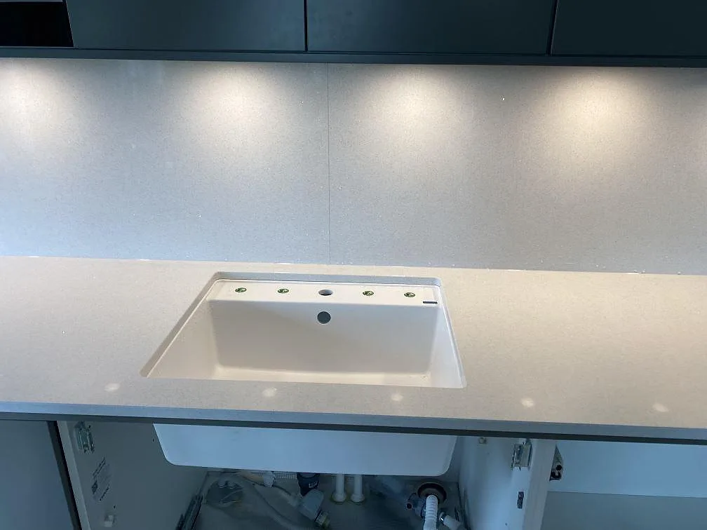 Underlimmad vit diskho i en polerad vit Brilliant White bänkskiva i ett kök i Malmö.