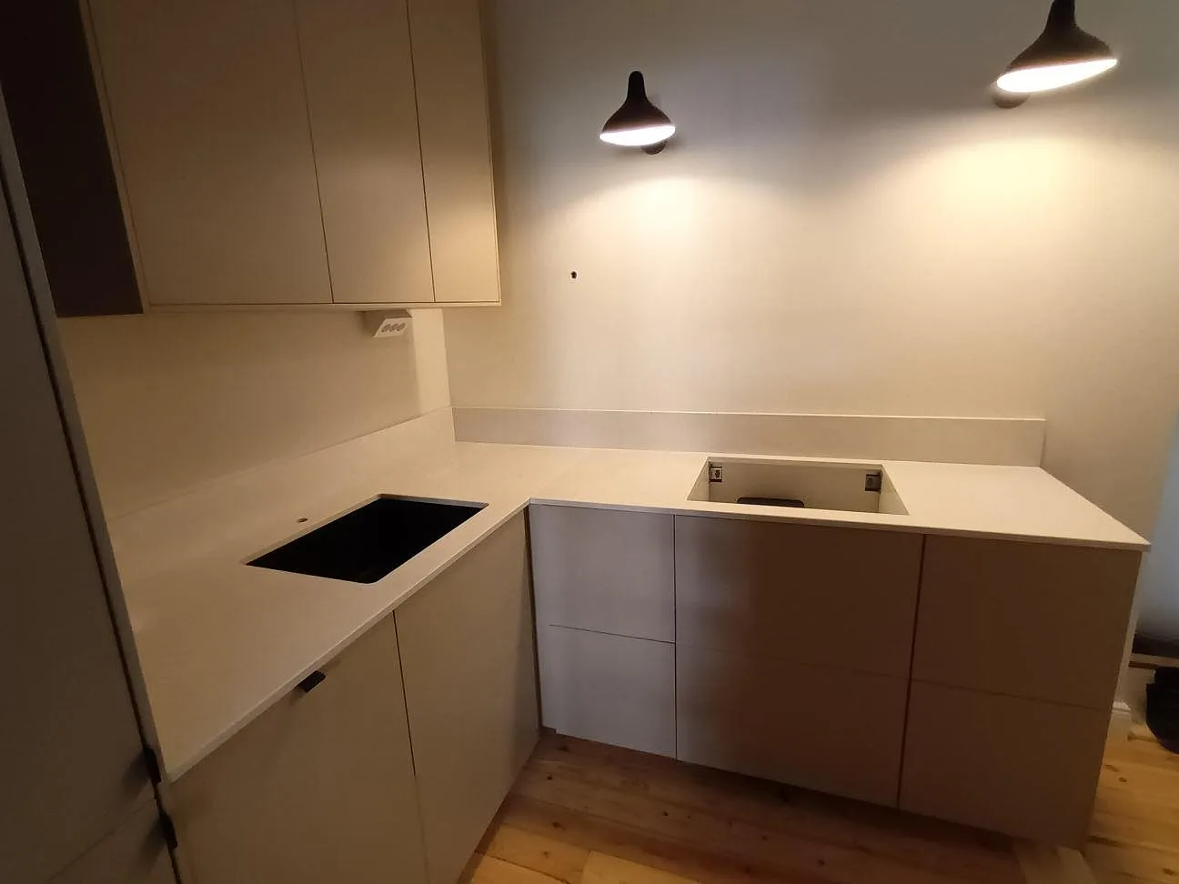 Köksbänkskiva i polerad Caesarstone Alpine Mist komposit med synlig hällöppning, diskhoöppning och låg stänkkant i ett kök i Stockholm.