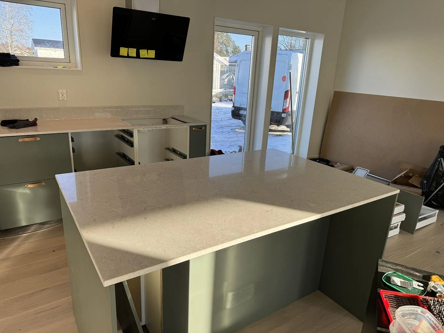 Köksbänkskiva i polerad Caesarstone Bianco Drift på köksö och väggbänk i ett kök under montering i Åsa.