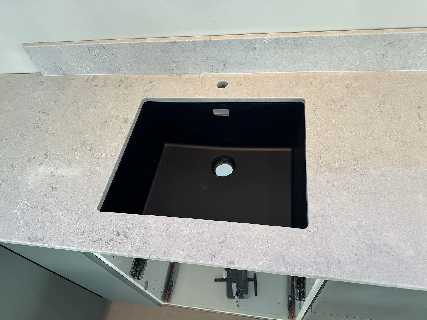 Svart underlimmad diskho i polerad Caesarstone Bianco Drift med låg stänkkant i ett kök i Åsa.