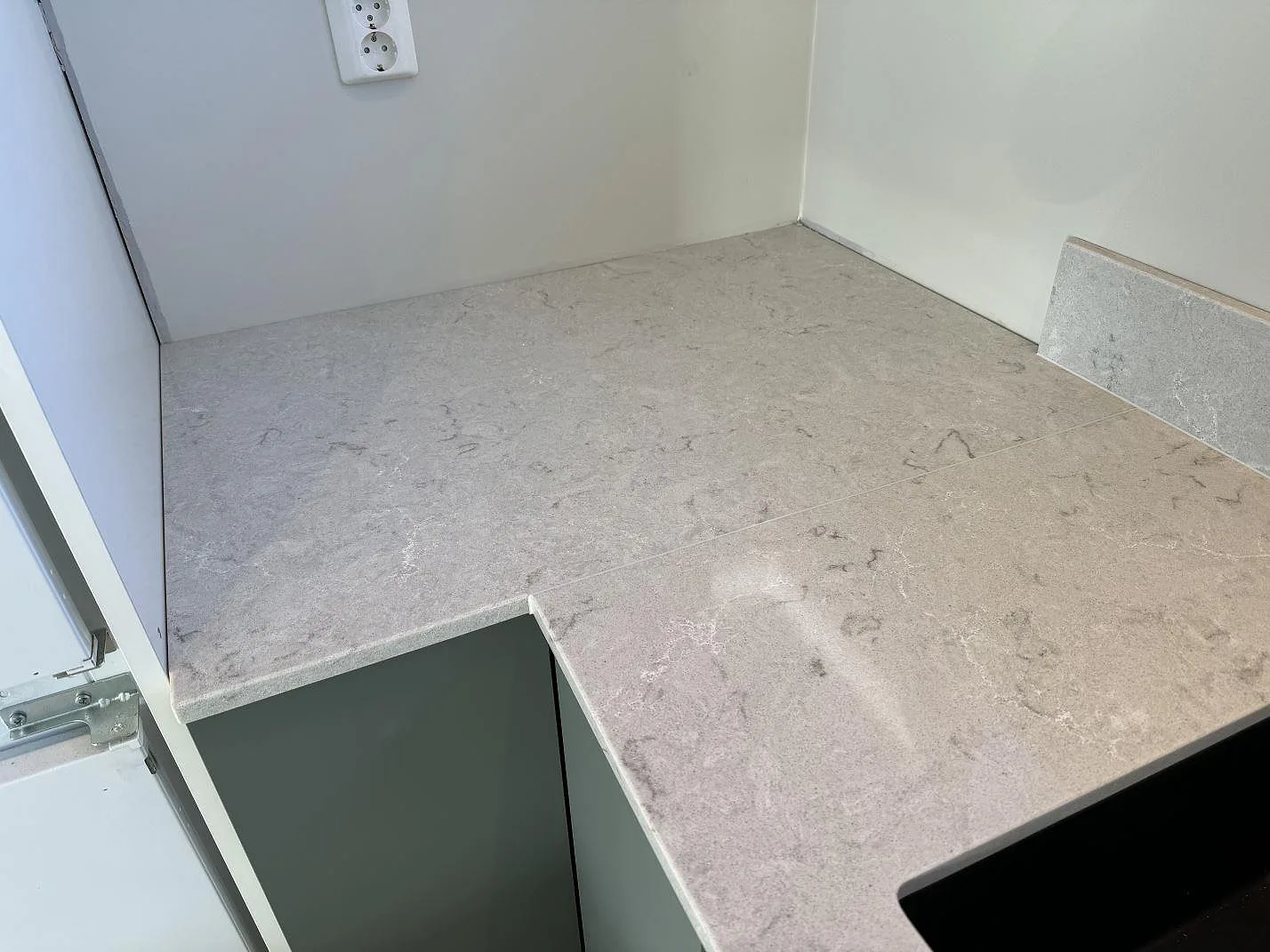 Hörndel av köksbänkskiva i polerad Caesarstone Bianco Drift med stänkkant och synlig ådring i Åsa.