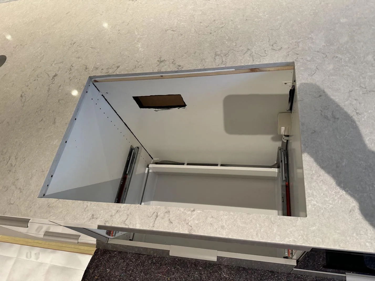 Närbild på hällöppning i 20 mm polerad Caesarstone Bianco Drift köksbänkskiva under montering i Halmstad.