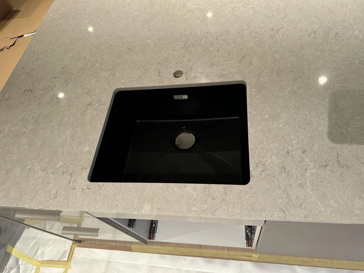 Detalj av svart underlimmad diskho i polerad Caesarstone Bianco Drift köksbänkskiva med ljus grå ådring i Halmstad.