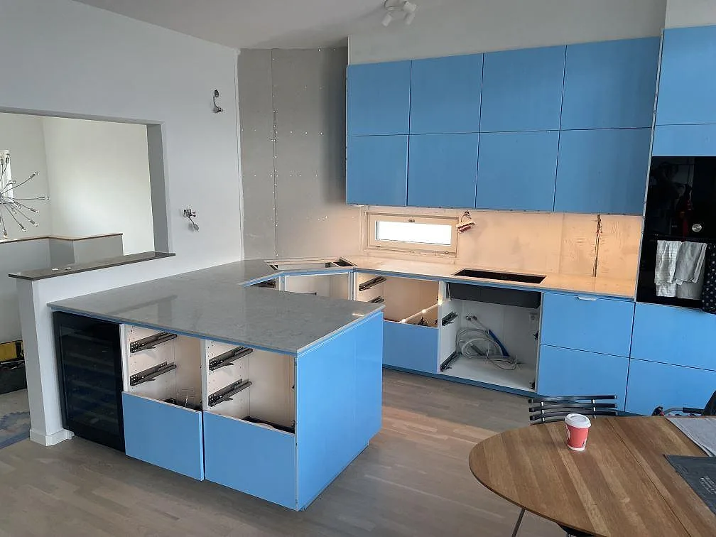 Köksbänkskiva i 20 mm polerad Caesarstone Bianco Drift, komposit, med köksö och väggbänk i ett kök i Lomma under montering.