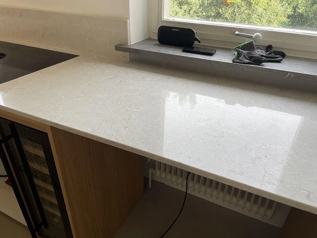 Blank polerad Caesarstone Bianco Drift köksbänkskiva med diskret ådring, fönsterljus och integrerad vinkyl i Malmö.