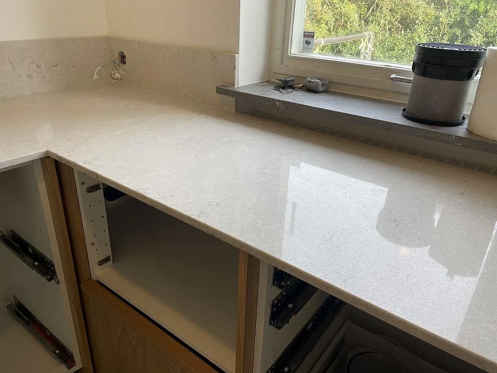 Lång arbetsyta vid fönster med polerad Caesarstone Bianco Drift bänkskiva, trästommar och ljus ådring i Malmö.