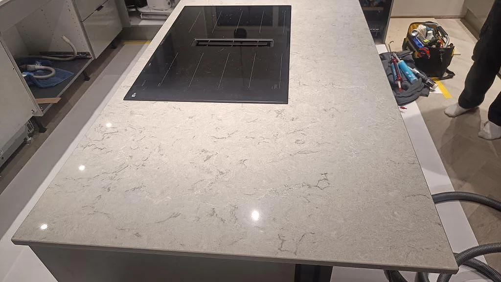Köksö i polerad Caesarstone Bianco Drift med infälld induktionshäll och ljus ådring i Tidaholm.