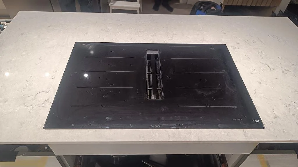 Närbild av induktionshäll i en polerad Caesarstone Bianco Drift köksö i Tidaholm.