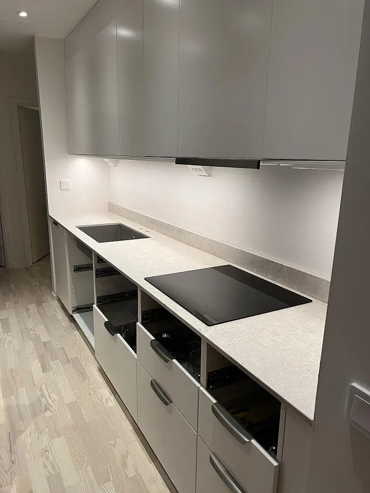 Köksbänkskiva i polerad Caesarstone Bianco Drift med häll och uppvikt stänkkant i ett kök i Uppsala.