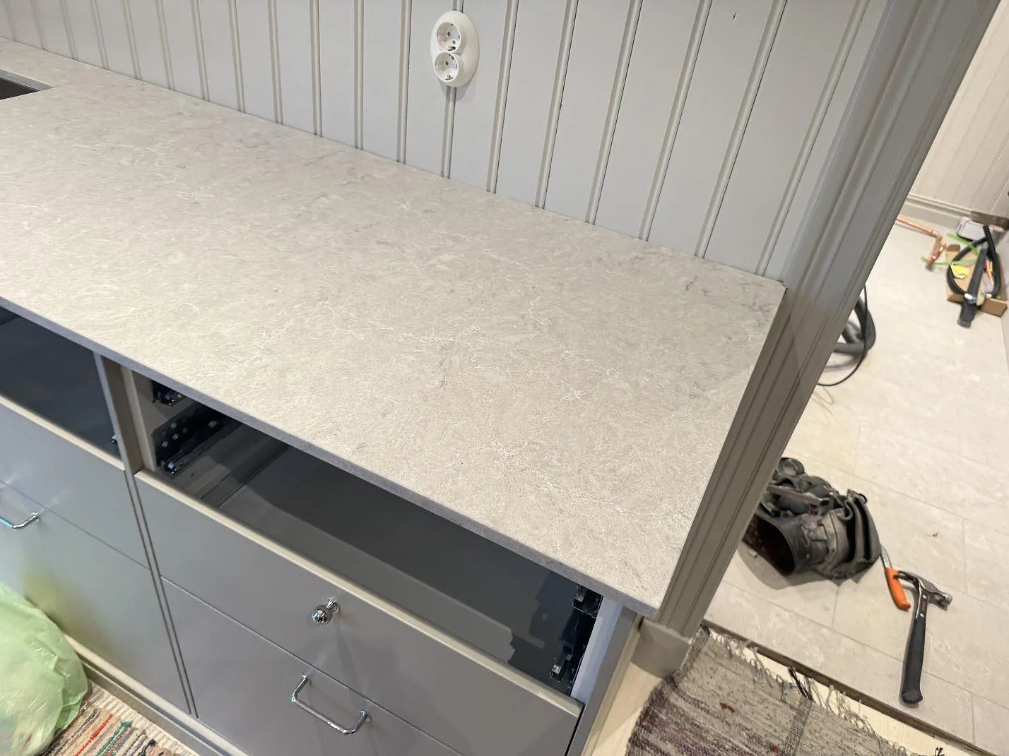 Bänk längs vägg i polerad Caesarstone Bianco Drift, monterad på grå köksstommar i Vårgårda.