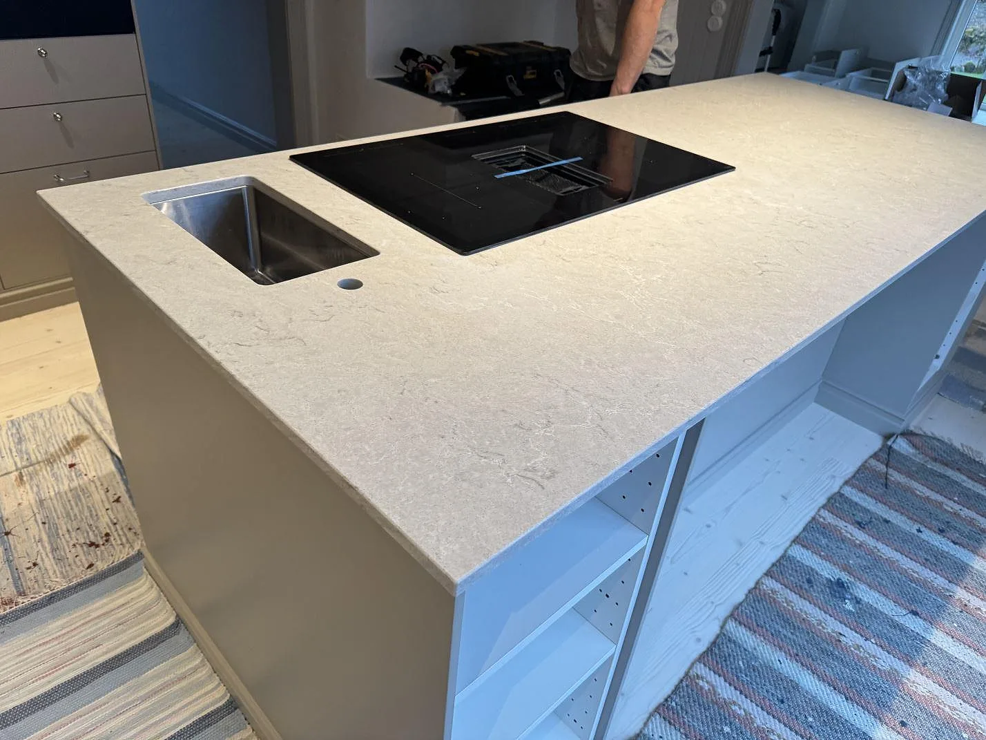 Närbild av köksö i polerad Caesarstone Bianco Drift med rostfri diskho, häll och ljus ådring i Vårgårda.