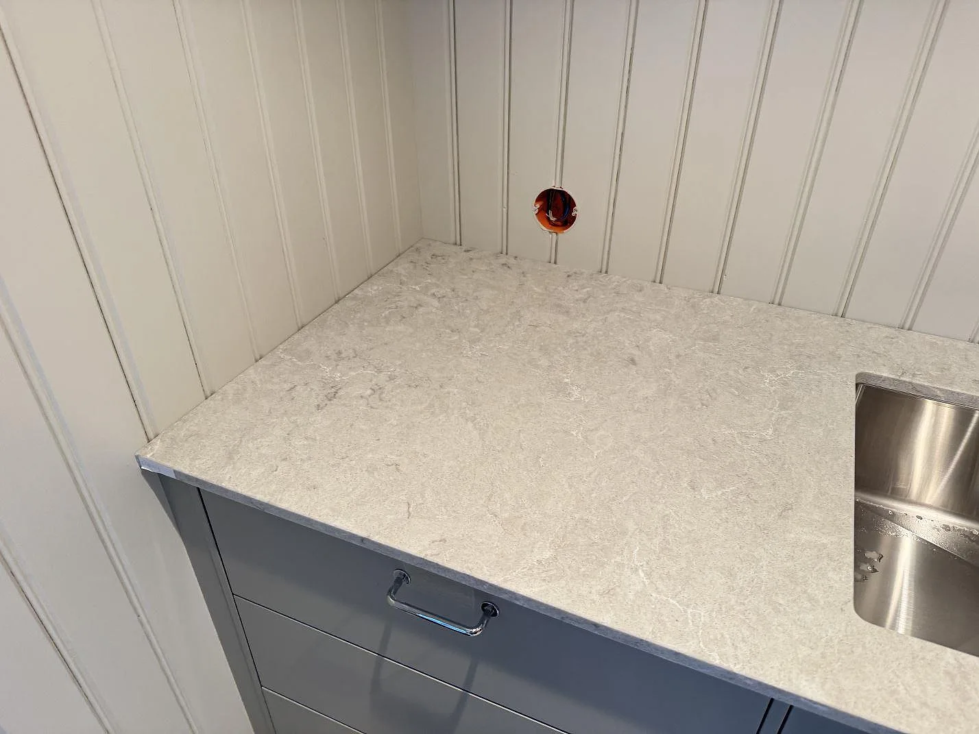 Ljus köksbänkskiva i polerad Caesarstone Bianco Drift med utskärning vid diskhon i Vårgårda.