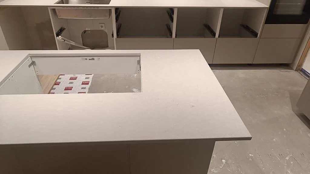 Köksö i matt Caesarstone Clamshell med hällöppning och ljus komposityta under montering i Åseda.
