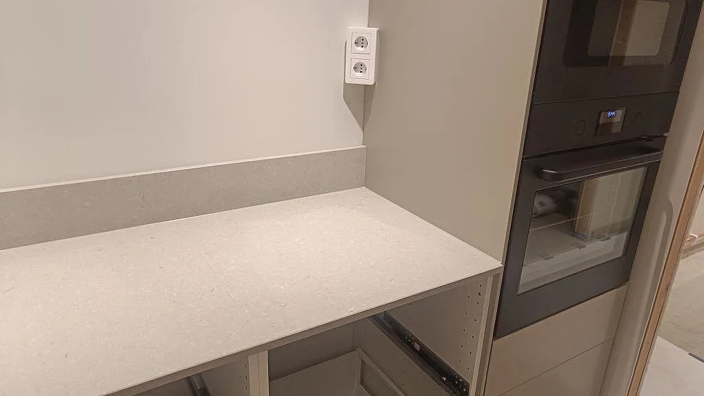 Bänkskiva i matt Caesarstone Clamshell med uppvikt stänkkant bredvid ugnsskåp i Åseda.