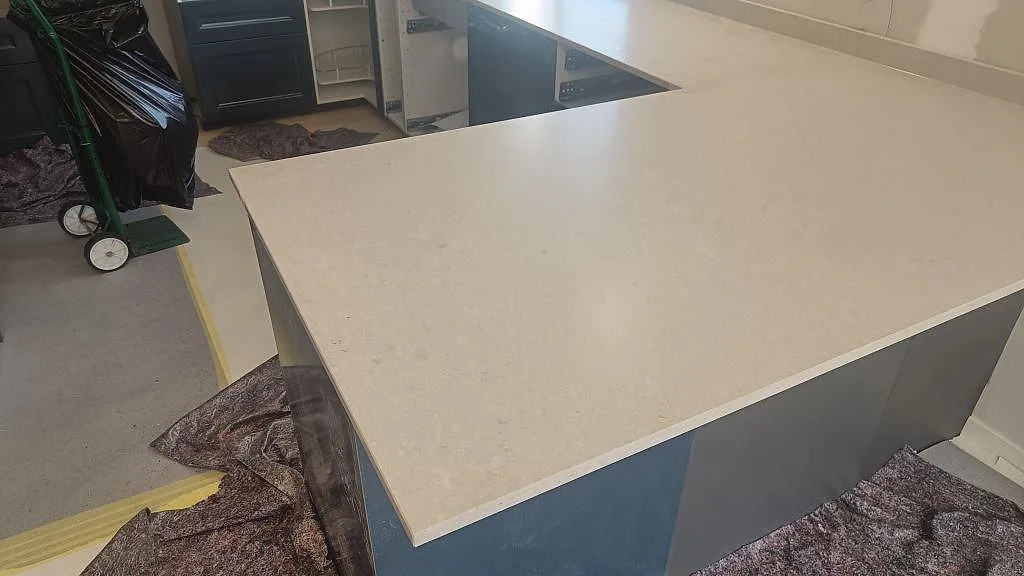 Närbild på matt Caesarstone Clamshell kvartskomposit som bänkskiva över köksö och hällöppning i Falköping.