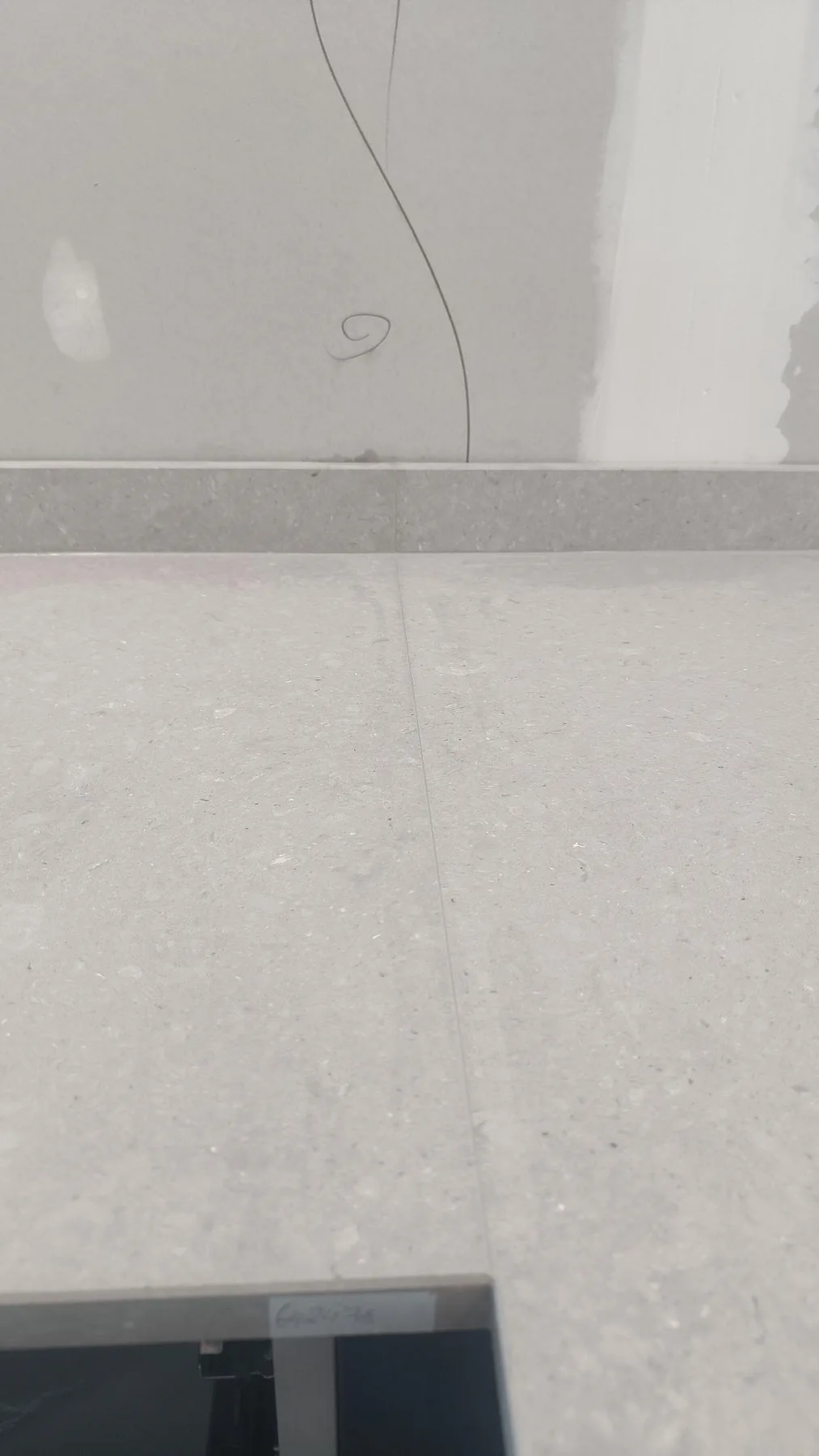 Vertikal detaljbild av matt Caesarstone Clamshell köksbänkskiva med skarv och stänkkant under montering i Falköping.