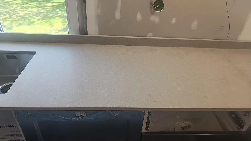 Rak köksbänk i matt Caesarstone Clamshell med hällöppning, stänkkant och gråblå stommar i Falköping.