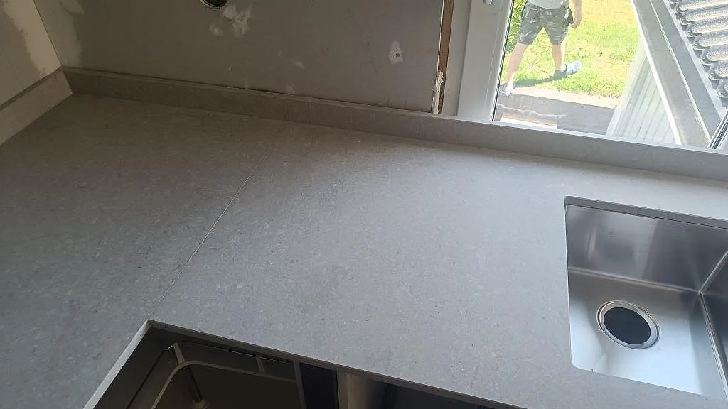 Matt Caesarstone Clamshell köksbänkskiva med dubbelho, fönster och låg stänkkant i ett kök i Falköping.