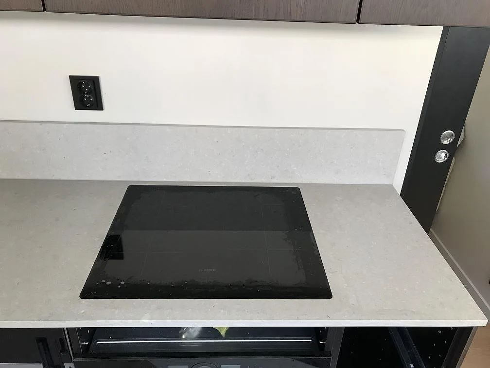 Infälld Bosch induktionshäll i matt beige köksbänkskiva av Caesarstone Clamshell med uppvikt stänkkant i ett kök i Göteborg.