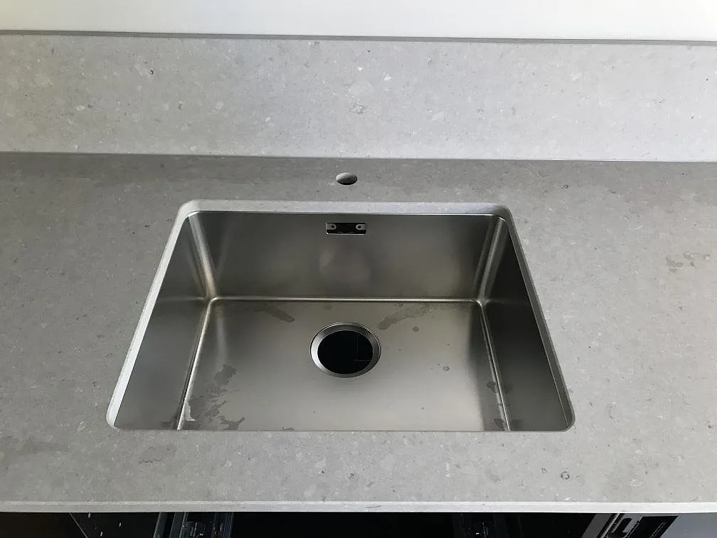 Underlimmad rostfri diskho i en matt beige köksbänkskiva av Caesarstone Clamshell i ett kök i Göteborg.