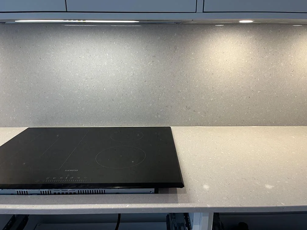 Infälld Siemens induktionshäll i en polerad bänkskiva i Caesarstone Clamshell komposit i ett kök i Halmstad.
