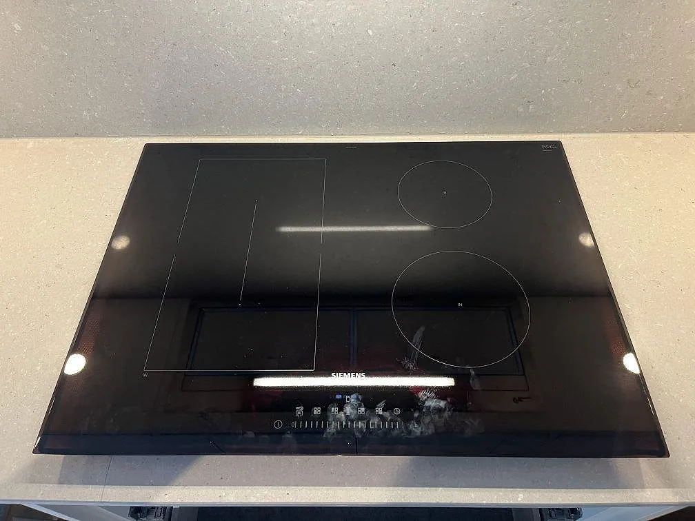 Närbild ovanifrån på en infälld induktionshäll i beige Caesarstone Clamshell bänkskiva i ett kök i Halmstad.