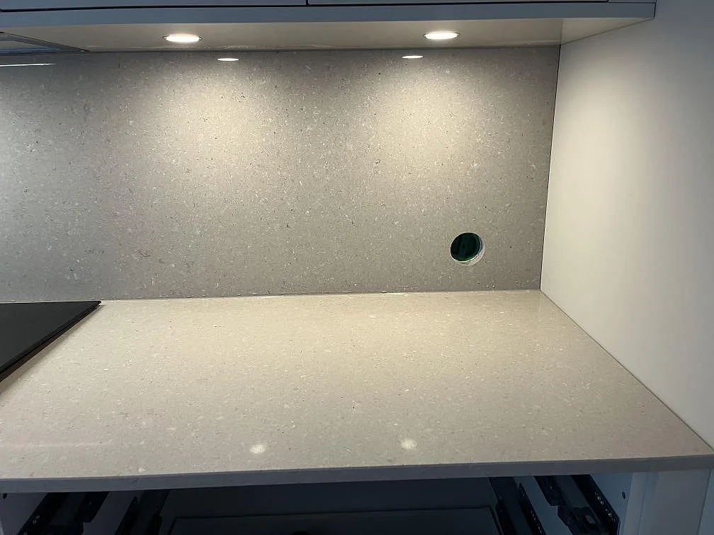 Polerad bänkskiva i Caesarstone Clamshell komposit med stänkvägg och uttag, fotad under montering i ett kök i Halmstad.