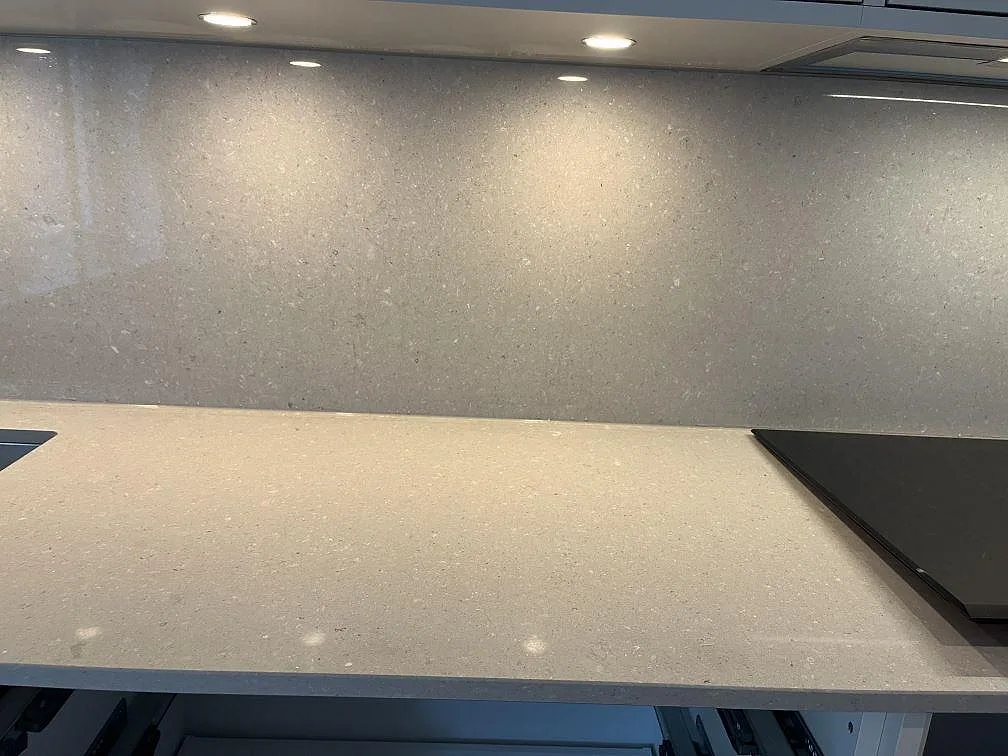 Beige köksbänkskiva i Caesarstone Clamshell med infälld induktionshäll och stänkvägg i ett kök i Halmstad.