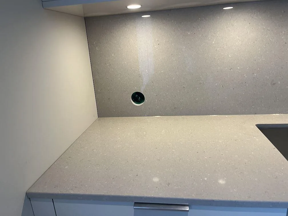 Köksbänkskiva i beige Caesarstone Clamshell med heltäckande stänkvägg i samma sten och underlimmad diskho i ett kök i Halmstad.