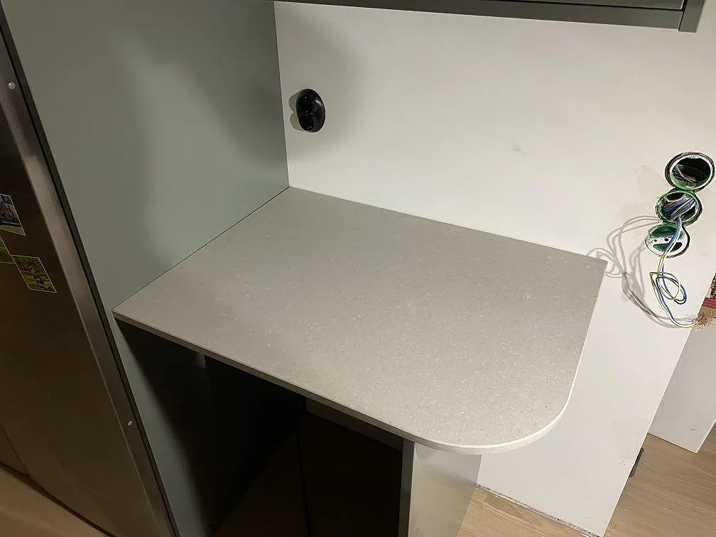 Sidobänk med rundad framkant i matt Caesarstone Clamshell, ljus kvartskomposit, monterad mot grågrön inredning i Lerum.