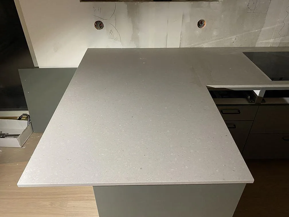 Bred arbetsyta i matt Caesarstone Clamshell, 20 mm kvartskomposit, monterad framför väggbänken i ett kök i Lerum.