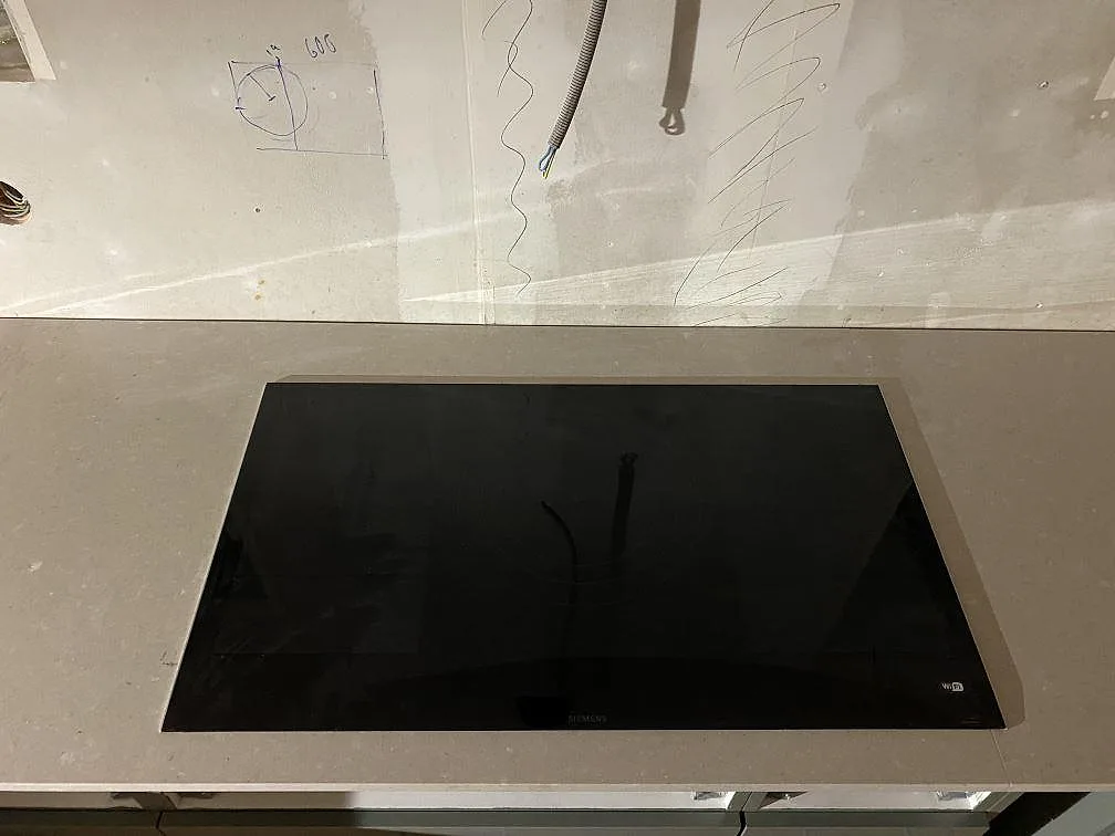 Köksbänkskiva i matt Caesarstone Clamshell med svart häll på den ljusgrå kompositstenen i Lerum.