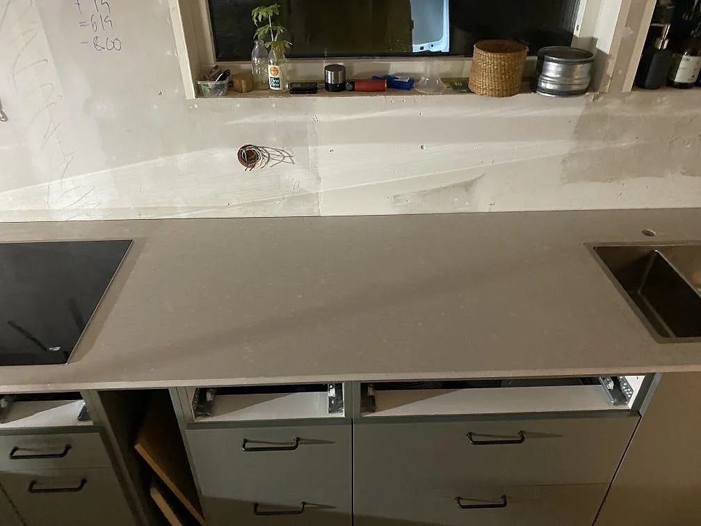 Lång köksbänkskiva i matt Caesarstone Clamshell med hällzon och diskho längs väggen i ett kök i Lerum.