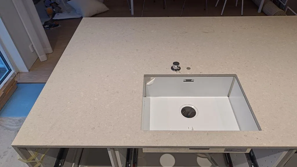 Närbild av bänkskiva i matt Caesarstone Clamshell med vit ho och ljus stenstruktur i Lomma.