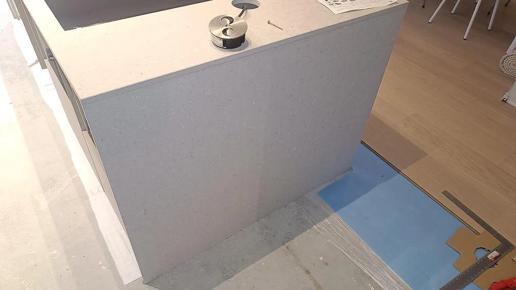 Sidoklädd köksö i matt Caesarstone Clamshell med ljus kvartskomposit och arbetsyta i Lomma.
