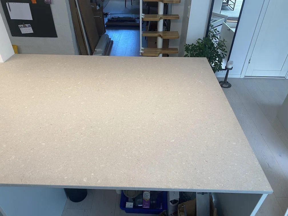 Köksbänkskiva och stor köksö i Caesarstone Clamshell, matt cremevit kvartskomposit, i ett ljust kök i Malmö.