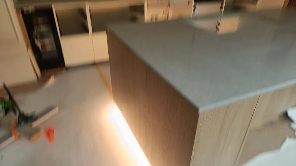 Översikt av kök under montering med stor köksö i polerad Caesarstone Clamshell komposit i Malmö.