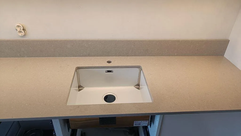 Närbild på underlimmad rostfri diskho i en polerad Caesarstone Clamshell bänkskiva med uppvikt stänkkant i Malmö.