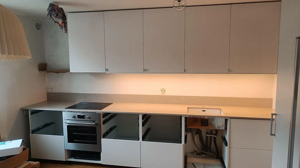 Köksbänkskiva i polerad Caesarstone Clamshell, 20 mm komposit, med underlimmad rostfri diskho och induktionshäll i Malmö.